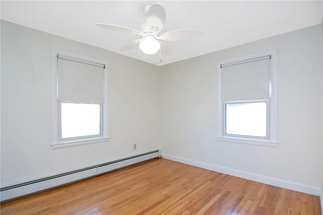 empty room featuring a baseboard heating unit, ceiling fan, and light hardwood / wood-style flooring