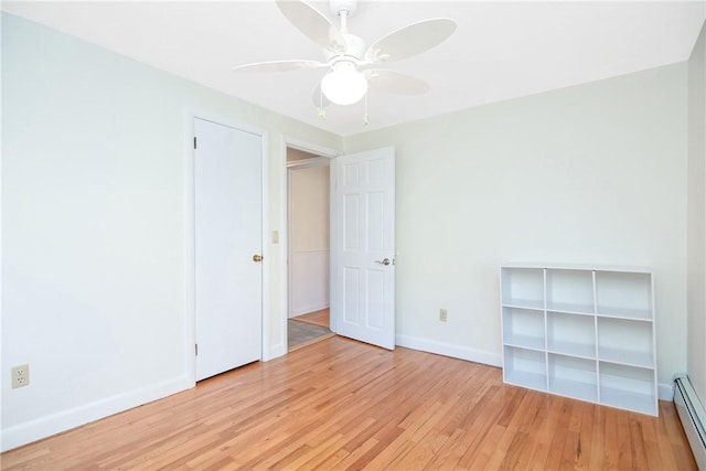 spare room featuring ceiling fan, a baseboard radiator, and light wood-type flooring