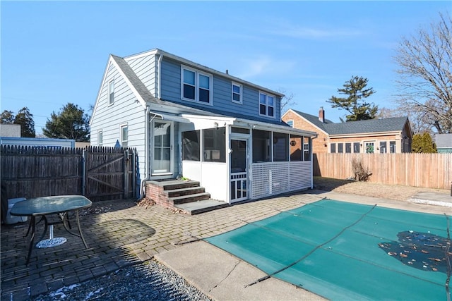 rear view of house with a patio, a sunroom, and a covered pool