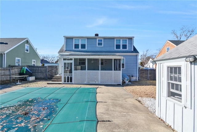 rear view of property featuring a sunroom, a patio, and a covered pool