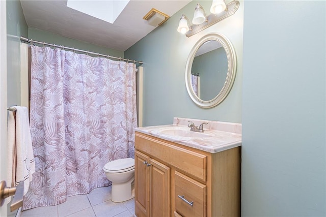 bathroom with tile patterned flooring, vanity, toilet, and a skylight