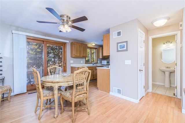 dining area with ceiling fan, sink, and light wood-type flooring