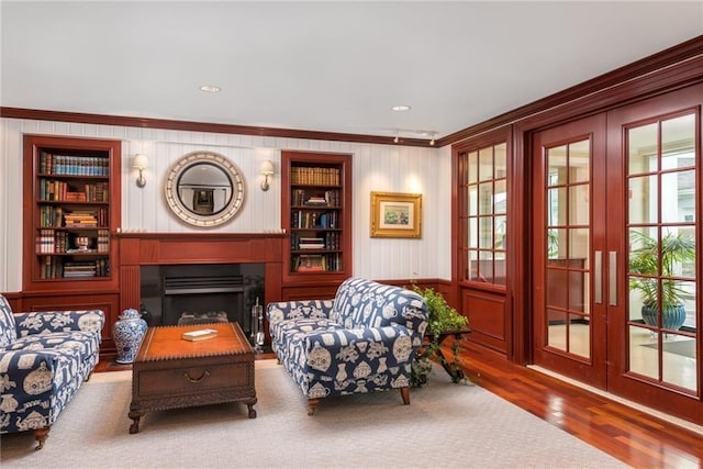 sitting room with ornamental molding, hardwood / wood-style floors, and built in shelves