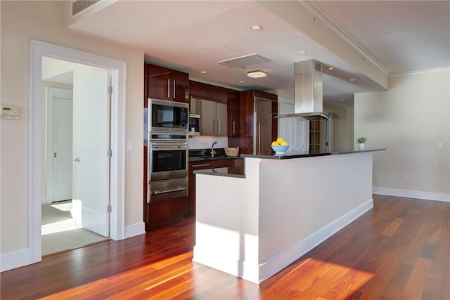 kitchen with built in microwave, dark brown cabinets, dark hardwood / wood-style flooring, island exhaust hood, and oven