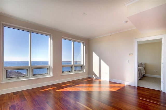 empty room with crown molding, dark hardwood / wood-style floors, and a water view