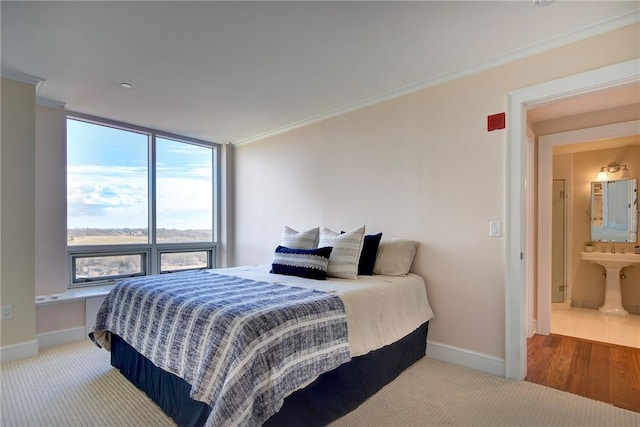 carpeted bedroom featuring ornamental molding and ensuite bathroom