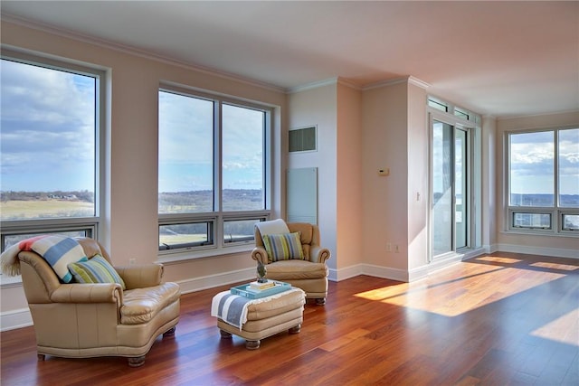 living area with crown molding, a healthy amount of sunlight, and hardwood / wood-style floors