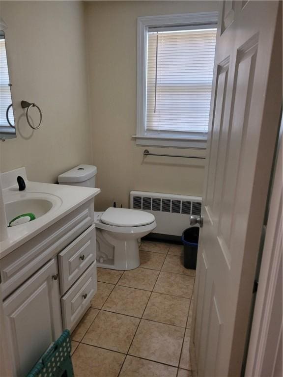 bathroom with tile patterned floors, toilet, vanity, plenty of natural light, and radiator