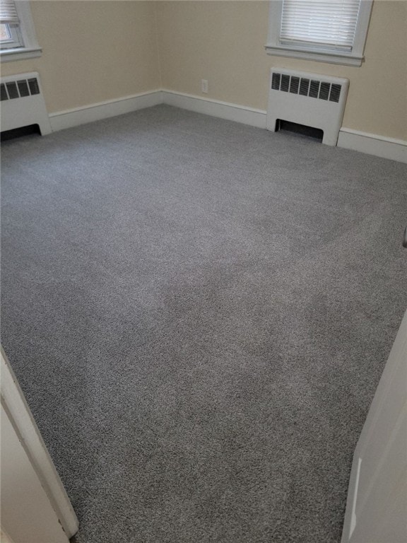 unfurnished living room with radiator heating unit, carpet, and plenty of natural light