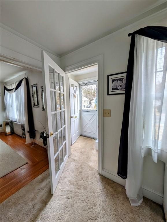 corridor with radiator heating unit, light colored carpet, and french doors