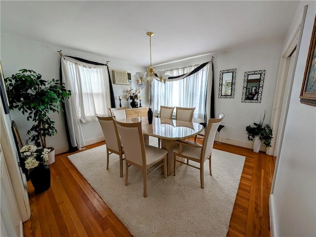 dining room with hardwood / wood-style flooring, a healthy amount of sunlight, an inviting chandelier, and a wall mounted air conditioner