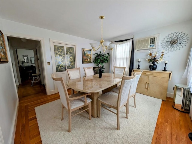 dining space with a wall mounted AC, hardwood / wood-style floors, and a notable chandelier