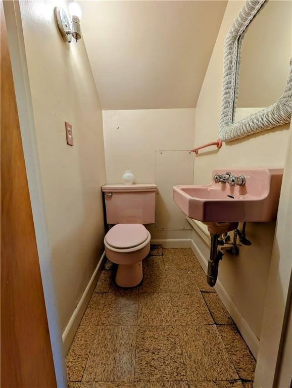 bathroom with vaulted ceiling, sink, and toilet