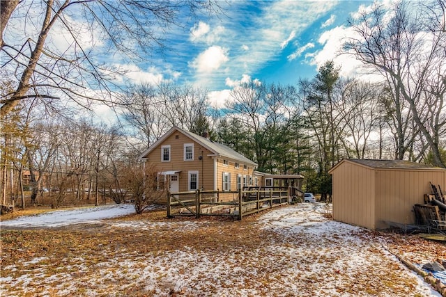 snow covered property featuring a wooden deck and a shed