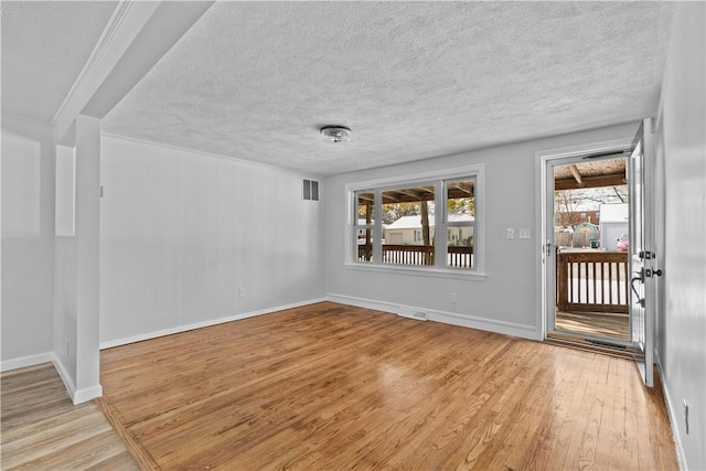 empty room with light hardwood / wood-style flooring and a textured ceiling