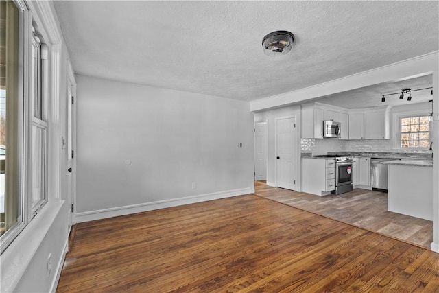 kitchen with a textured ceiling, appliances with stainless steel finishes, dark hardwood / wood-style flooring, white cabinets, and backsplash