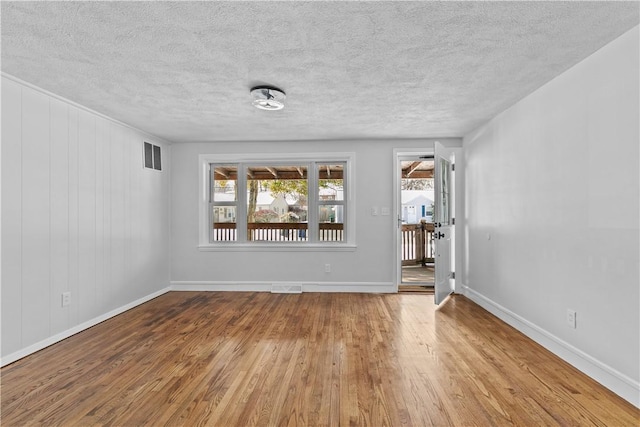 empty room featuring hardwood / wood-style floors, a wealth of natural light, and a textured ceiling