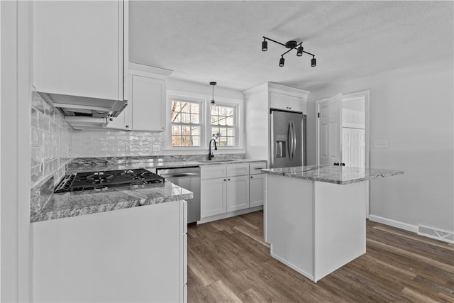 kitchen featuring sink, appliances with stainless steel finishes, a center island, white cabinets, and decorative light fixtures