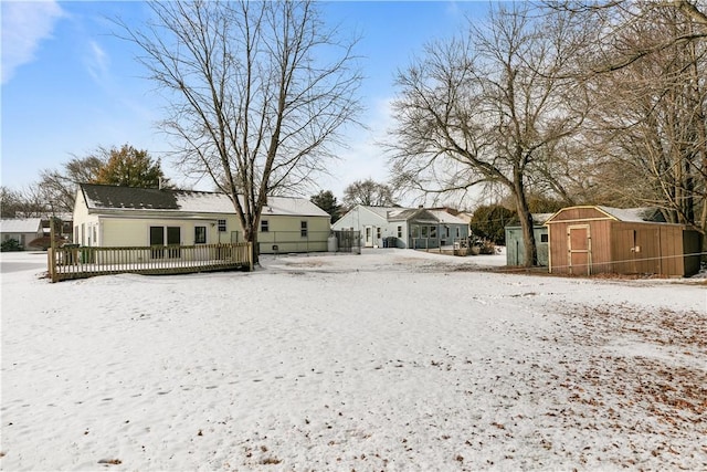 snow covered rear of property with a storage shed