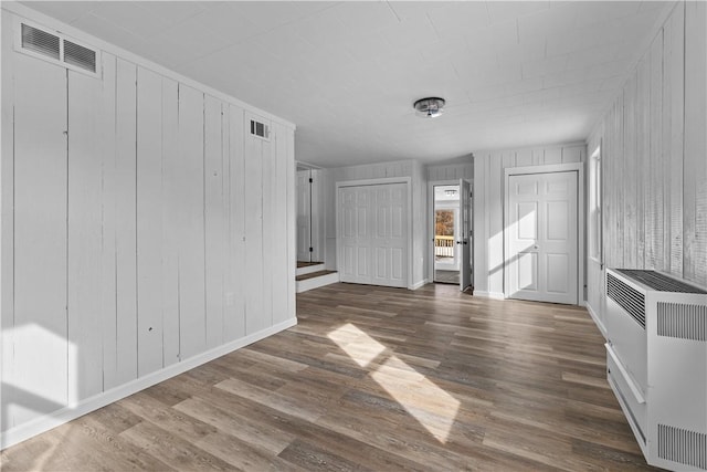 unfurnished living room with dark hardwood / wood-style floors and heating unit