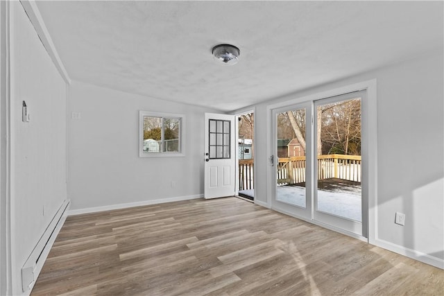 unfurnished room with a baseboard radiator and light hardwood / wood-style flooring