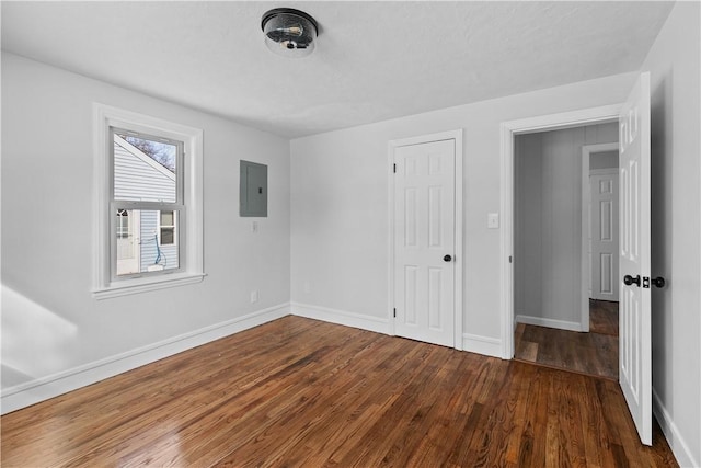 unfurnished bedroom with dark hardwood / wood-style flooring, electric panel, and a closet