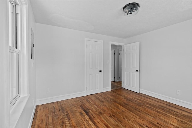 unfurnished bedroom with dark hardwood / wood-style flooring and multiple windows