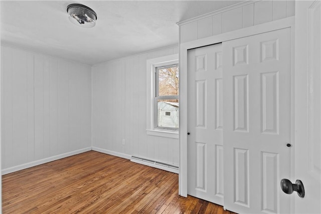 unfurnished bedroom featuring a baseboard heating unit, a closet, and light wood-type flooring