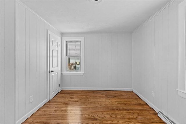 unfurnished room with wood-type flooring and a baseboard heating unit