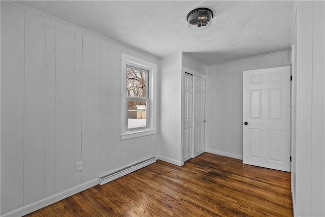 unfurnished bedroom with dark hardwood / wood-style flooring, baseboard heating, and a closet