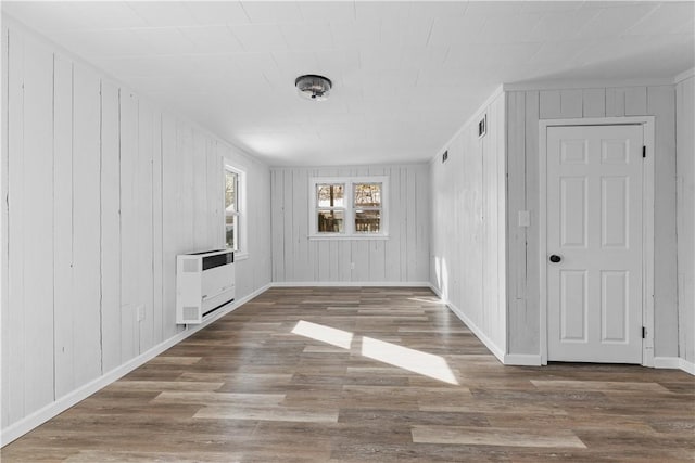 unfurnished room featuring wood-type flooring and heating unit