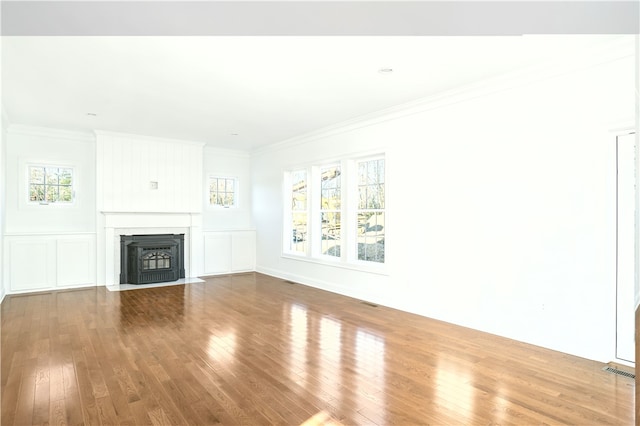 unfurnished living room with crown molding, wood-type flooring, and a healthy amount of sunlight