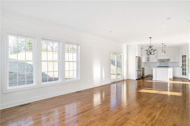 unfurnished living room featuring dark hardwood / wood-style flooring, a notable chandelier, and ornamental molding