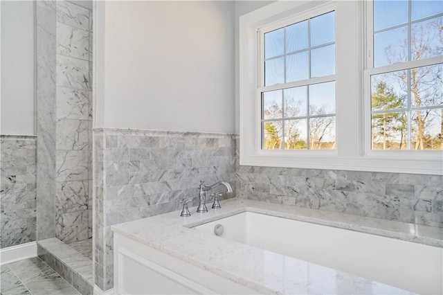 bathroom featuring shower with separate bathtub and tile walls