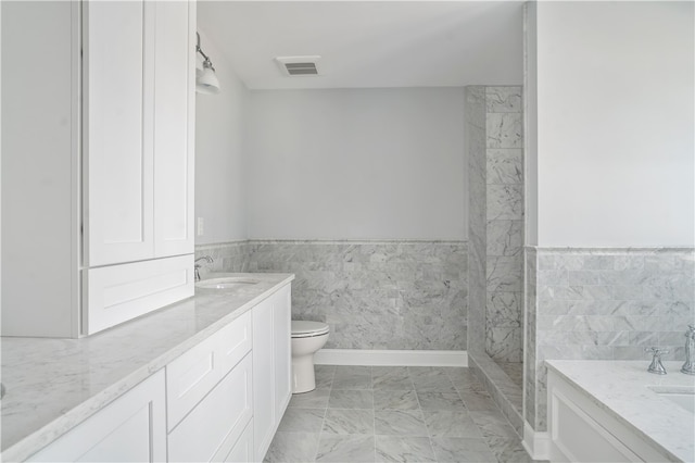 bathroom featuring vanity, toilet, and tile walls