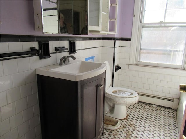 bathroom with tile walls, vanity, toilet, and baseboard heating