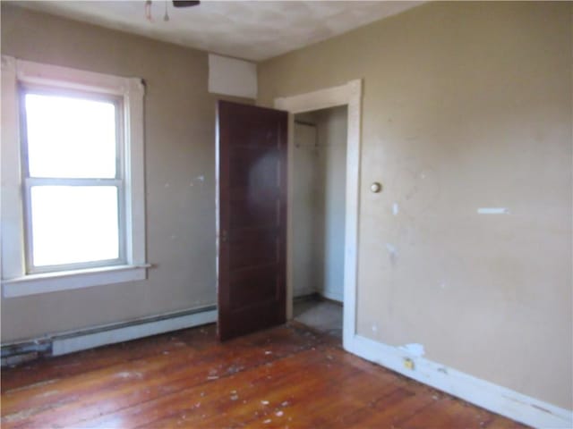 unfurnished bedroom featuring dark hardwood / wood-style flooring and a baseboard heating unit