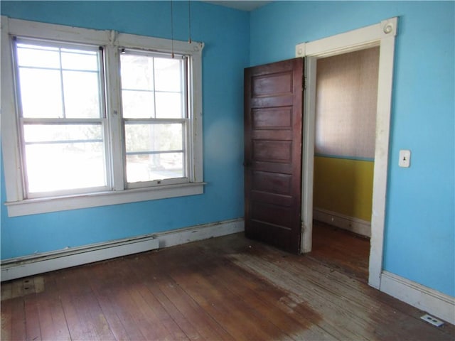 unfurnished room featuring dark hardwood / wood-style flooring, a wealth of natural light, and baseboard heating