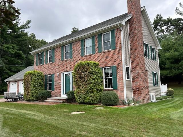 colonial inspired home with a garage and a front lawn