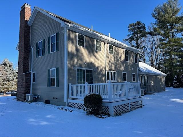 snow covered back of property featuring a deck