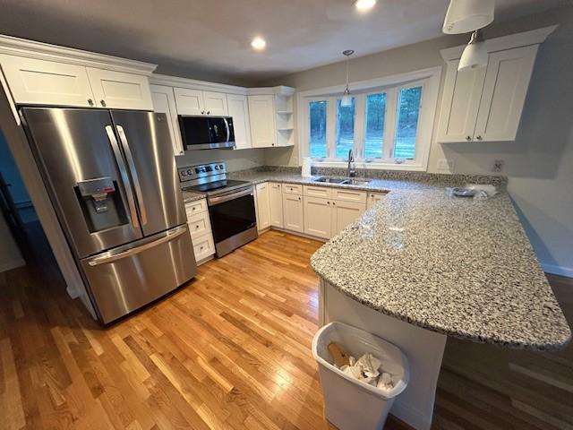 kitchen featuring stainless steel appliances, white cabinetry, sink, and kitchen peninsula