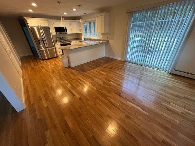 kitchen with dark wood-type flooring, appliances with stainless steel finishes, kitchen peninsula, pendant lighting, and white cabinets