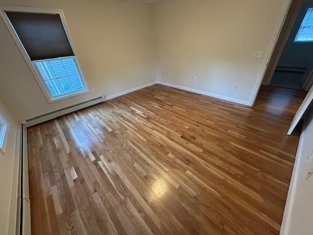 unfurnished room featuring hardwood / wood-style floors and baseboard heating