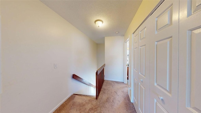 hallway with light colored carpet and a textured ceiling