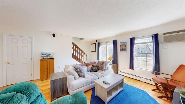 living room featuring a baseboard radiator, a wall mounted air conditioner, a textured ceiling, and light wood-type flooring