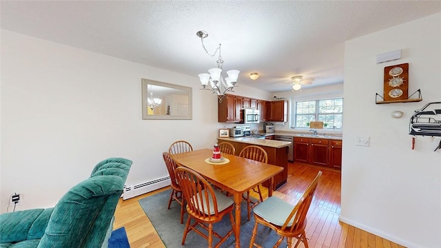 dining room featuring sink, a baseboard heating unit, an inviting chandelier, and light hardwood / wood-style floors