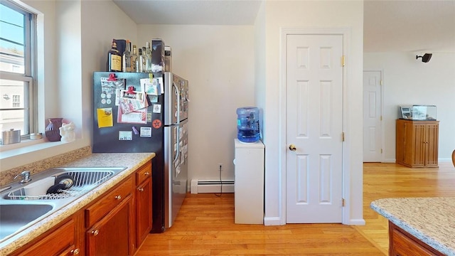 kitchen featuring a baseboard radiator, sink, stainless steel fridge, and light hardwood / wood-style flooring