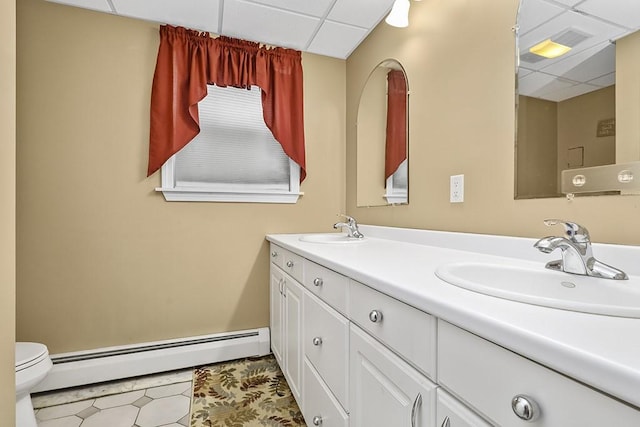 bathroom featuring a drop ceiling, vanity, toilet, and baseboard heating