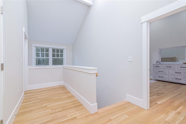 hall with lofted ceiling and light hardwood / wood-style flooring