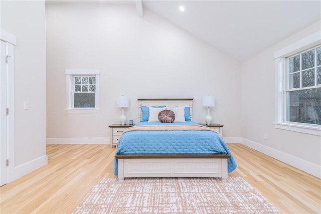 bedroom featuring multiple windows, high vaulted ceiling, light wood-type flooring, and beamed ceiling